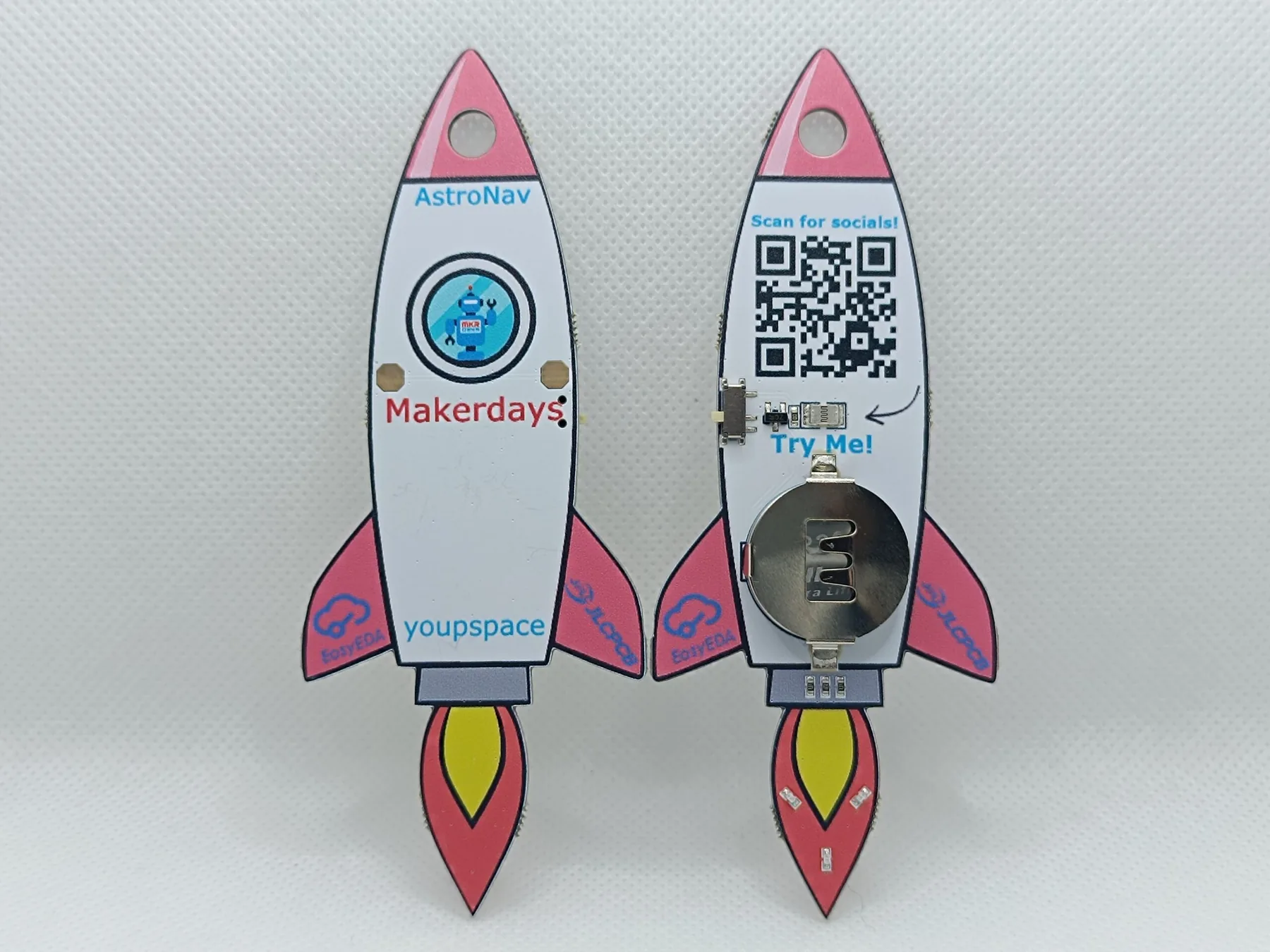 Front and back of two rocket-shaped Maker Days PCB keychains